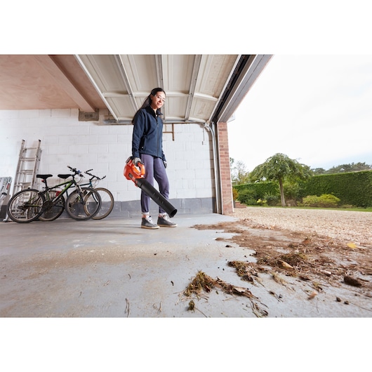 BLACKDECKER BCBL200L40 leaf blower used in garage to clear debris, ground-level photography.