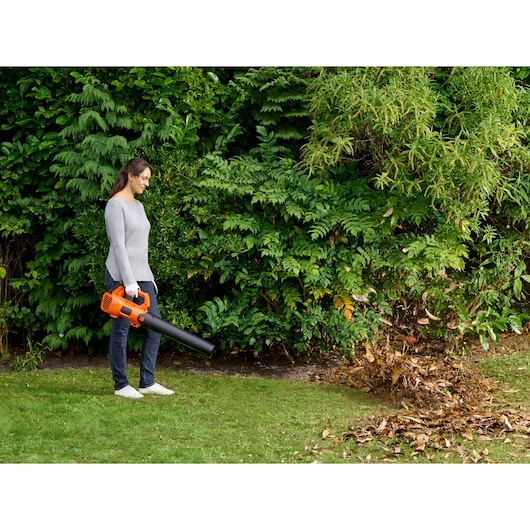 BLACKDECKER BCBL200L40 cordless leaf blower in use, blowing leaves in a garden.