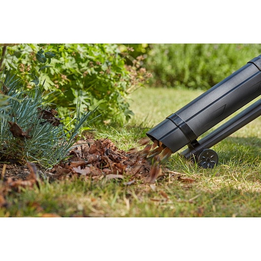 BLACKDECKER BCBLV3625L1 garden vacuum blowing leaves onto grass, close-up side view.