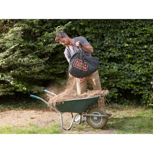 BLACK+DECKER BCBLV3625L1 garden vacuum debris bag being emptied into a wheelbarrow outdoors.