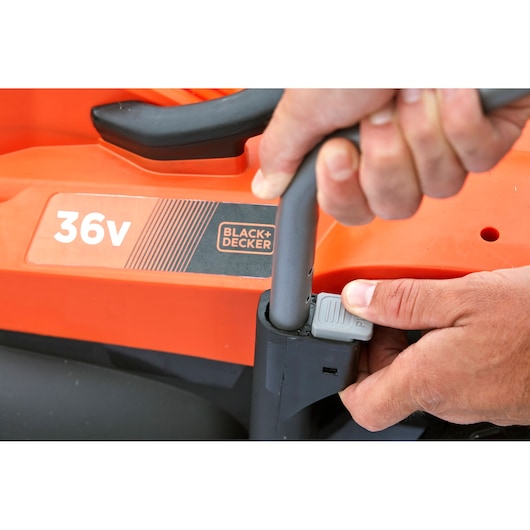 Close-up photo of BLACK+DECKER BCMW3336L1 lawn mower handle being adjusted, showing orange 36v body and control.