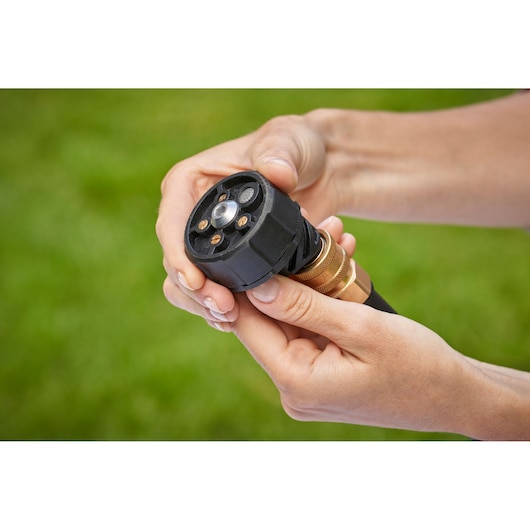 Photo of BLACKDECKER BCPC18B pressure washer nozzle held in hands, black and brass finish, outdoor setting.