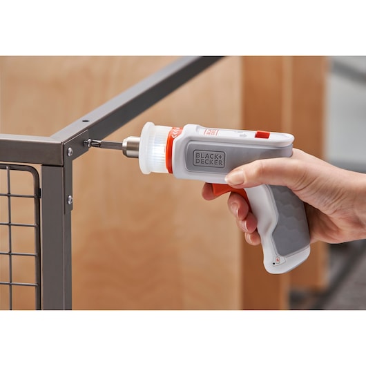 BLACK+DECKER BCRTA01 cordless screwdriver in use fastening screw to metal frame.