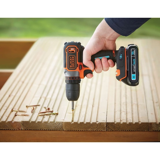 Photo of BLACKDECKER BDCDC18KST cordless drill in use on wooden planks, visible screws, outdoor setting.