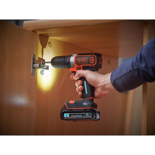 BLACKDECKER BDCDC18KST cordless drill used on cabinet hinge, LED light, smarttech battery visible.