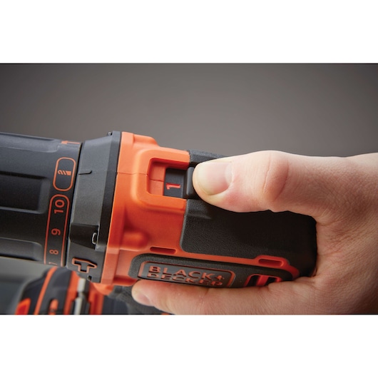Close-up photo of hand adjusting speed setting on BLACK+DECKER cordless drill BDCHD18KB2, black and orange design.