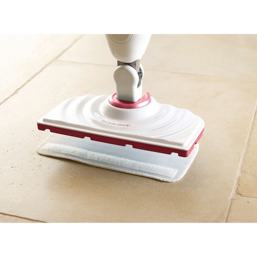 BLACKDECKER BDS1616R steam mop head in white and pink cleaning beige tile floor, side angle.