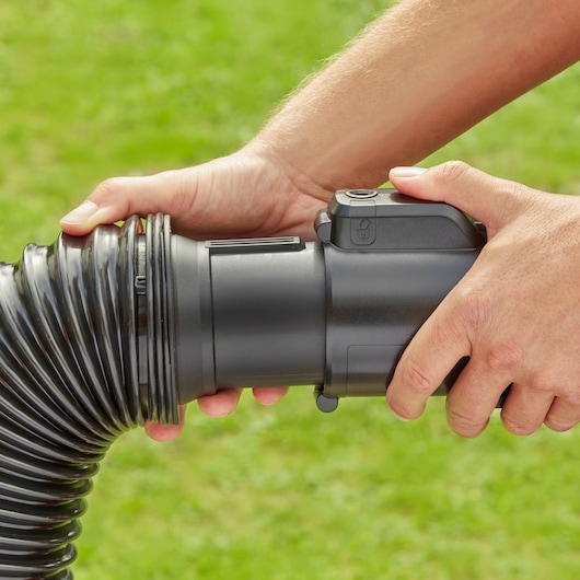 Photo of hands connecting BLACK+DECKER BEBLV230 leaf blower hose outdoors.