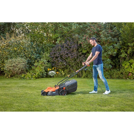 Photo of BLACKDECKER BEMW481ES electric lawn mower on grass, corded, being used outdoors.