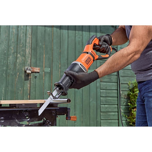 BLACK+DECKER BES301 reciprocating saw in use cutting metal pipe outdoors, close-up view.