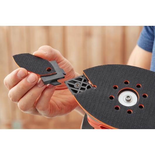 BLACKDECKER BEW200 detail sander pad attachment close-up held by hand, showing accessory installation.