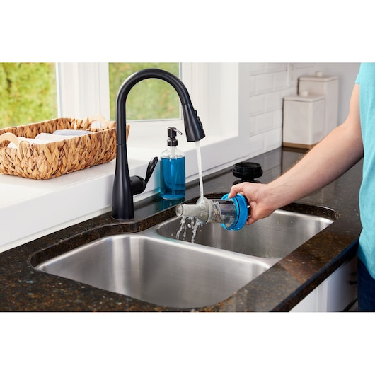 BLACKDECKER BHFEB520D1 vacuum filter being rinsed under a kitchen faucet into a sink.