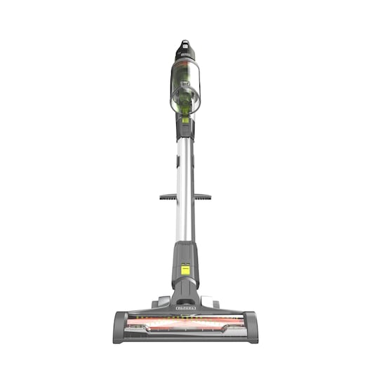 Front view of a BLACK+DECKER cordless stick vacuum cleaner with a transparent dust container, grey and silver body, and wide cleaning head, standing upright against a white background.