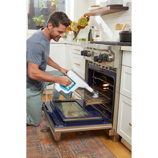 BLACKDECKER BHSM15FX08 steam cleaner used on oven rack in modern kitchen setting.