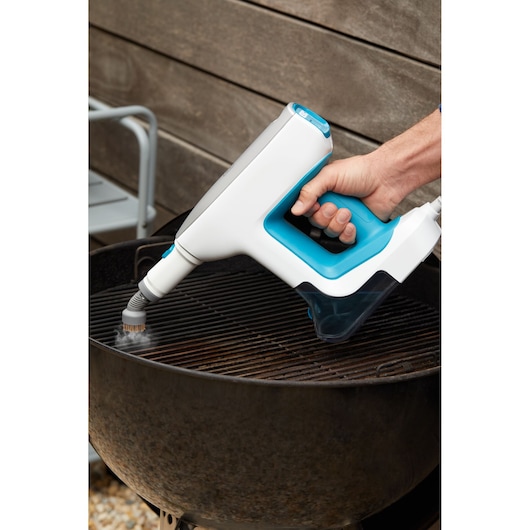BLACK+DECKER BHSM15FX08 handheld steam cleaner with blue handle cleaning barbecue grill outdoors.