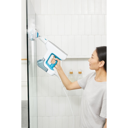 Photo of BLACKDECKER steam cleaner BHSM15FX08 cleaning a glass shower door in a bathroom setting.