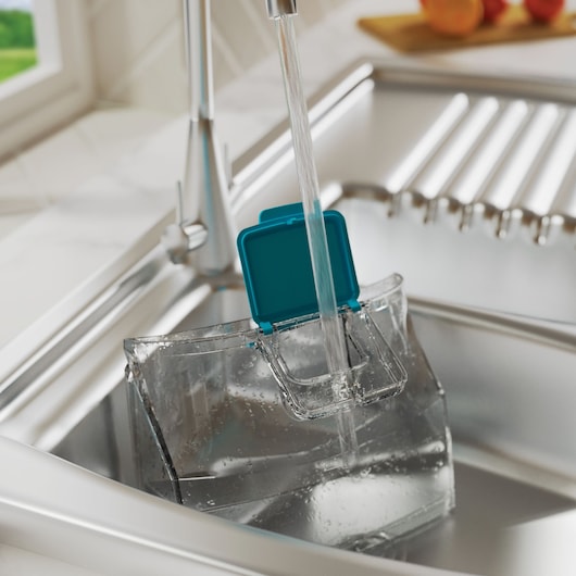 BLACKDECKER BHSMP2008 clear water tank with teal lid being filled at kitchen sink, side angle.