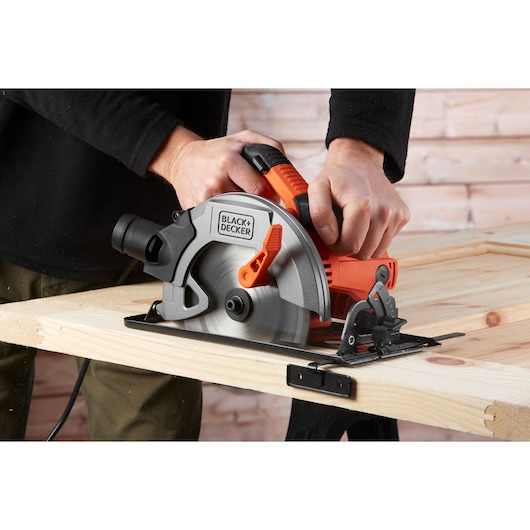 BLACKDECKER CS1550 circular saw in use cutting wood, showing blade and ergonomic handle.