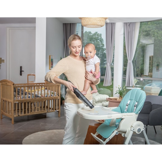 BLACKDECKER DVC320B21 handheld vacuum being used to clean high chair tray in a modern living room setting.