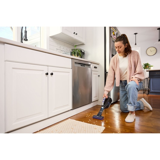 Photo of BLACK+DECKER handheld vacuum DVD320BP cleaning crumbs on a kitchen floor.