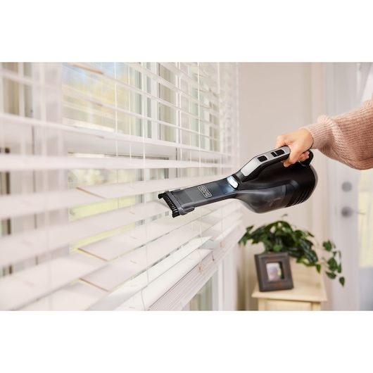 BLACKDECKER DVD320J handheld vacuum cleaning window blinds indoors, black design, product photography.