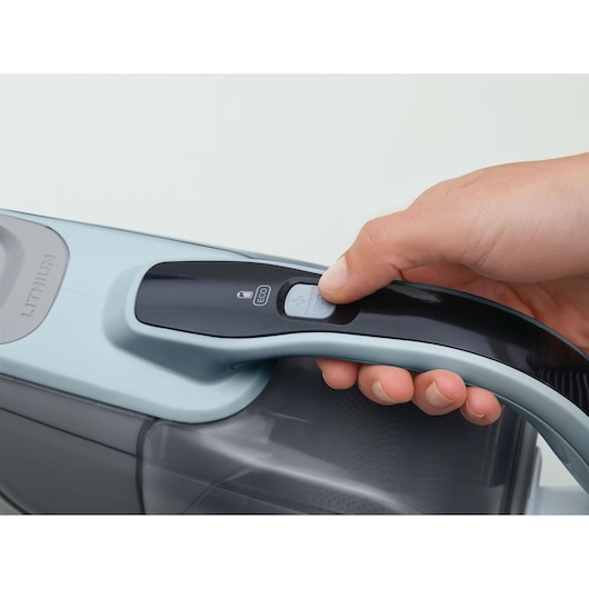 BLACKDECKER DVJ325J handheld vacuum close-up, hand pressing eco mode button, side angle.