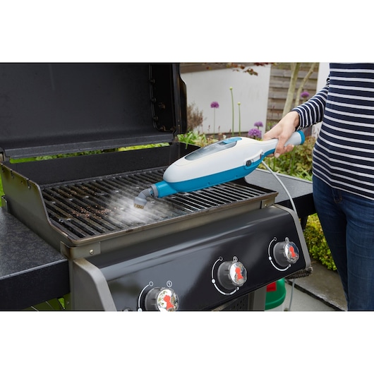 BLACKDECKER FSMH13E10 steam cleaner used on outdoor grill grates, product in action view.