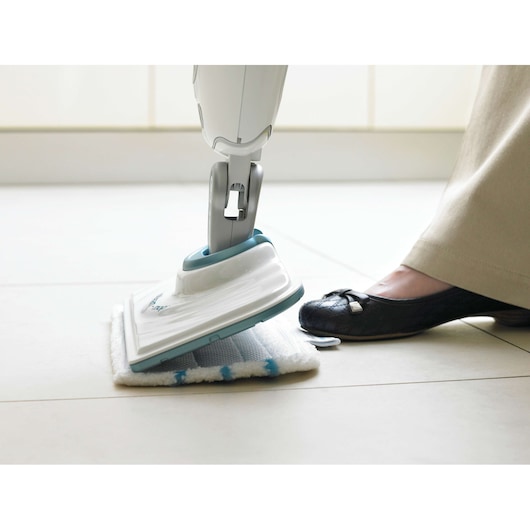 BLACKDECKER FSMP20 steam mop head with white and blue microfiber pad, foot pressing the pad on tile floor.