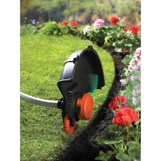 BLACKDECKER GL933 lawn trimmer in use edging grass border near colorful flowers.