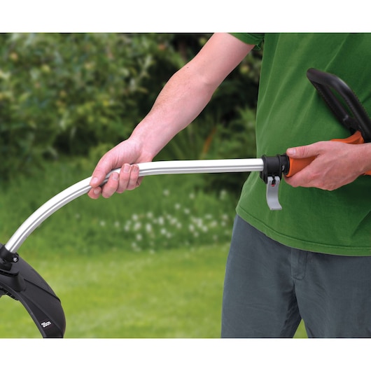 BLACKDECKER GL933 grass trimmer shown in use outdoors, close-up of adjustable handle and silver shaft.