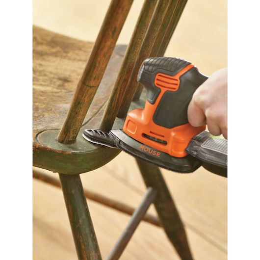 BLACKDECKER KA2500K sander in use refinishing an old wooden chair, close-up view.