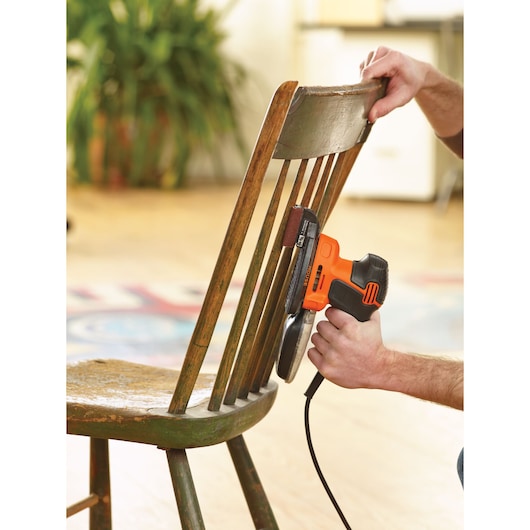 Photo of BLACK+DECKER KA2500K orange and black electric sander used on a wooden chair.