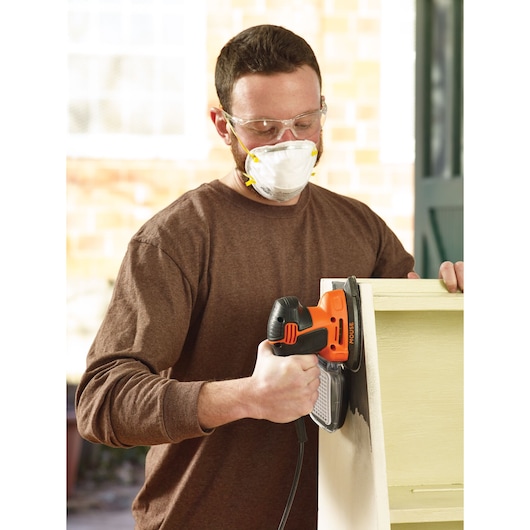 BLACKDECKER KA2500K detail sander in use on wood furniture, shown in workshop setting.