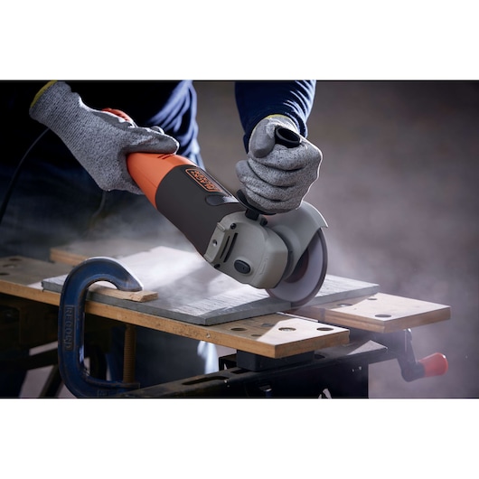 BLACKDECKER KG1202 angle grinder in use, cutting tile on workbench, gray and orange body.