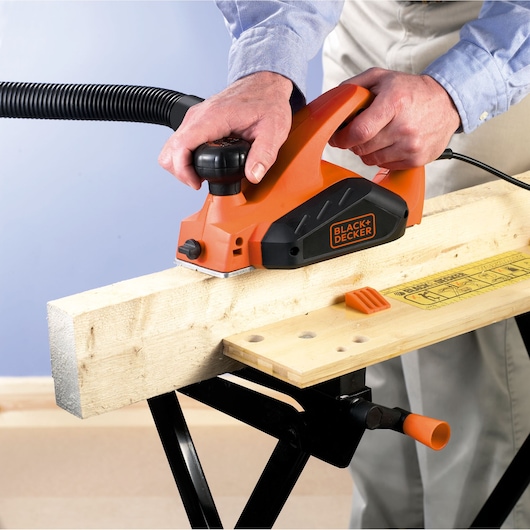 Photo of BLACK+DECKER KW712 electric hand planer in use smoothing wooden beam.