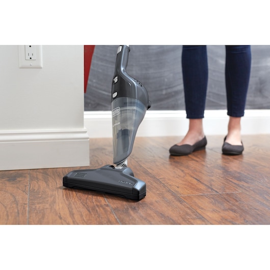 BLACKDECKER NSVA315J cordless stick vacuum in use on wood floor, person standing nearby.