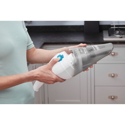 Photo of BLACK+DECKER NVC115JL handheld vacuum being opened by hand in a kitchen setting.