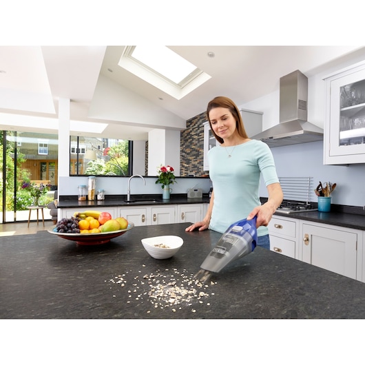BLACKDECKER NVC115WA hand vacuum cleaning kitchen counter, fruit bowl and cereal visible.