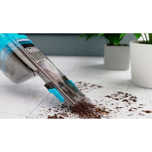 BLACKDECKER NVD215J handheld vacuum cleaner picking up dirt on tile floor, close-up view.