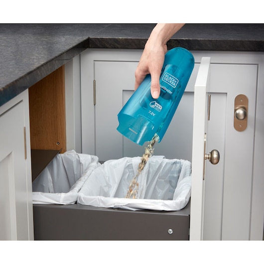 BLACKDECKER WDC215WA handheld vacuum canister being emptied into a kitchen trash bin.