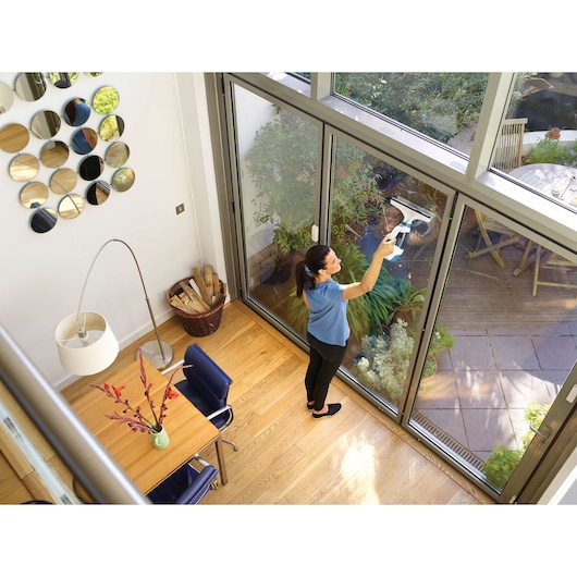 BLACKDECKER WW100 window cleaning tool used on glass door in modern living room with wooden floor.